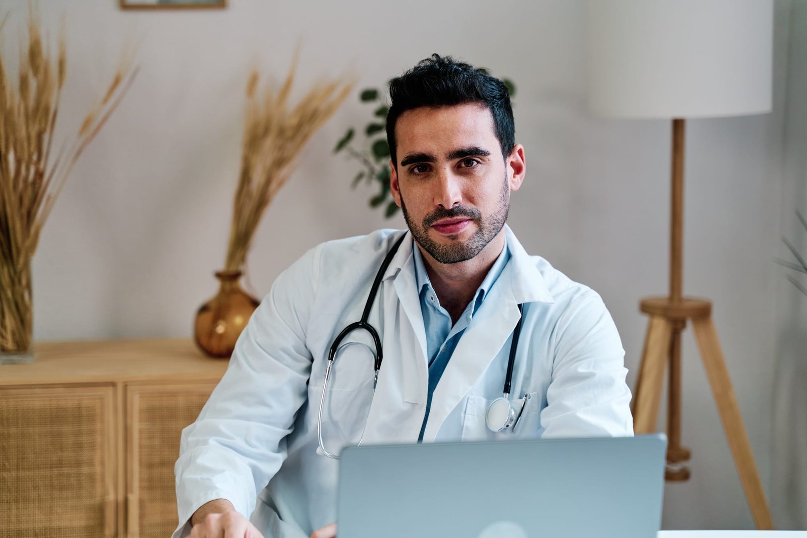 Cheerful ethnic doctor using laptop
