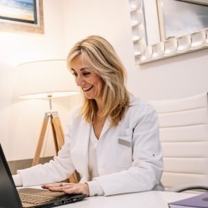 Cheerful doctor using laptop in office
