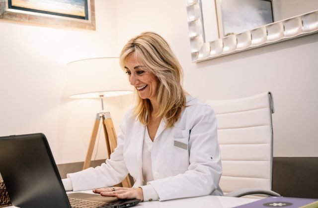 Cheerful doctor using laptop in office