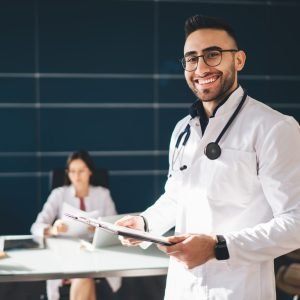 Cheerful male doctor in medical uniform working in hospital