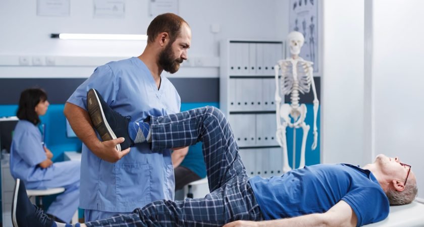 Chiropractor assisting senior patient