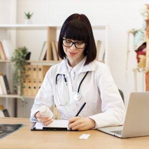 Female doctor writing prescription in medical office