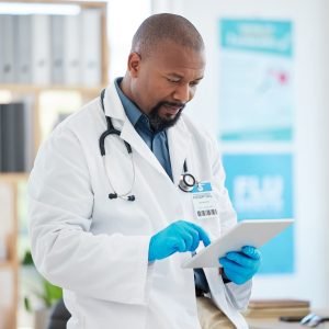 Focused doctor using a digital tablet in his clinic office. African american specialist using an on