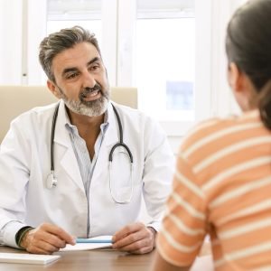 Happy male doctor talking to female patient in clinic