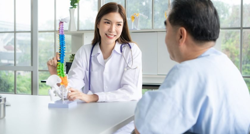In the hospital office, A medical explains about the spine and its treatment to a patient