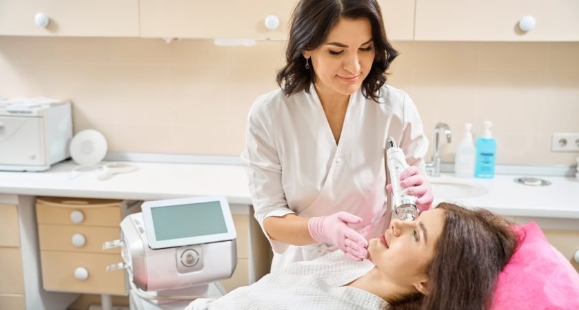 Qualified dermatologist carrying out RF microneedling on young woman